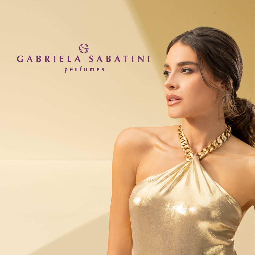 Gabriela Sabatini com vestido dourado e colar, ao lado do logo 'Gabriela Sabatini perfumes'. Campanha da fragrância.